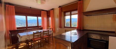 A kitchen with wooden cabinets, a granite countertop, and a dining area with a table and chairs.