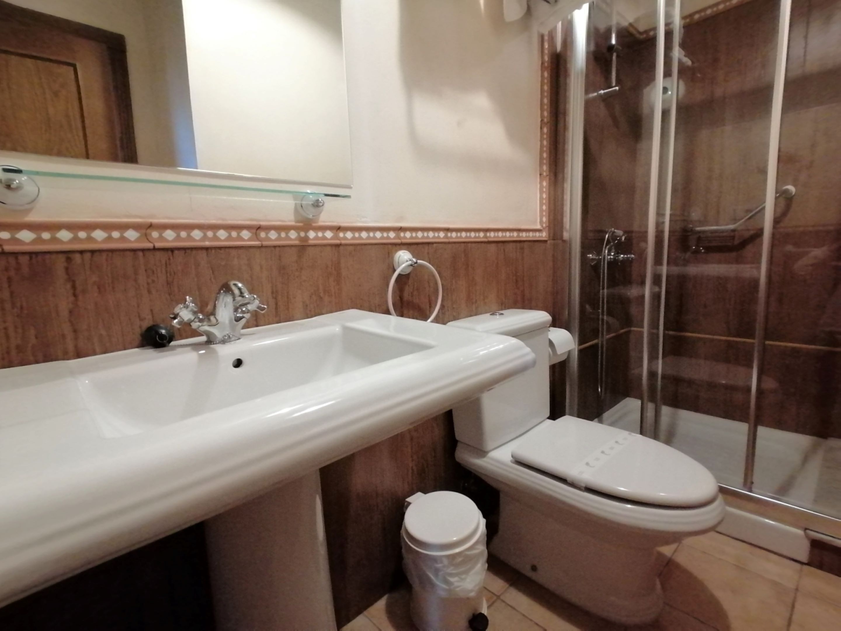 Et badeværelse med vask, toilet og brusekabine i glas.
