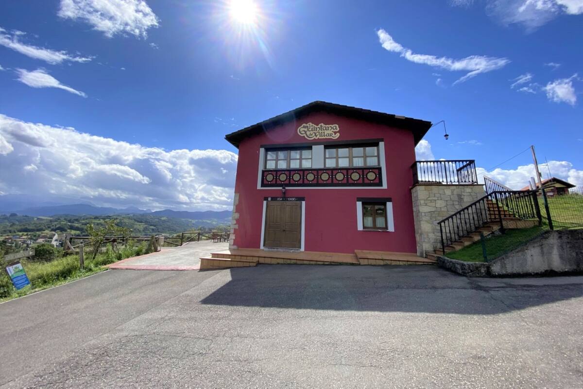 Un bâtiment rouge avec une enseigne indiquant « Kintana Villa » et un escalier menant à l’entrée.
