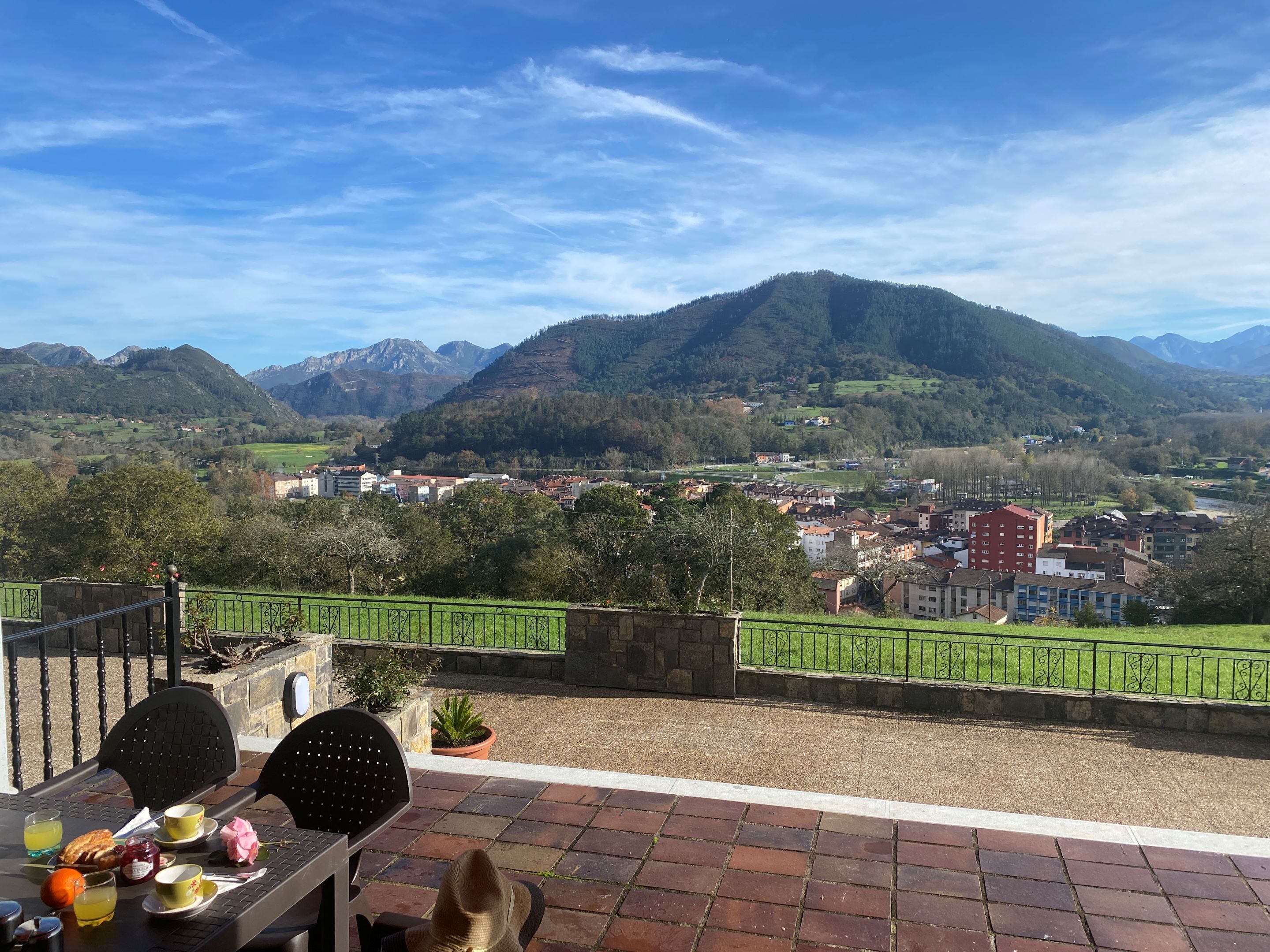 Een terras met een ontbijttafel, met uitzicht op een bergachtig landschap en een stad daaronder.