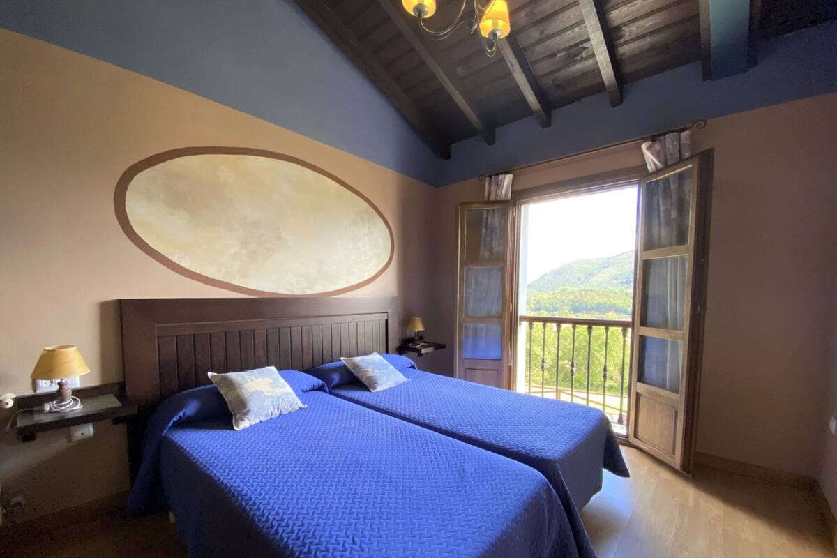 Une chambre avec deux lits, un grand élément de décoration ovale sur le mur et un balcon donnant sur l’extérieur.