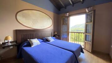 A room with two beds, a large oval wall decoration, and a balcony with a view of the outdoors.