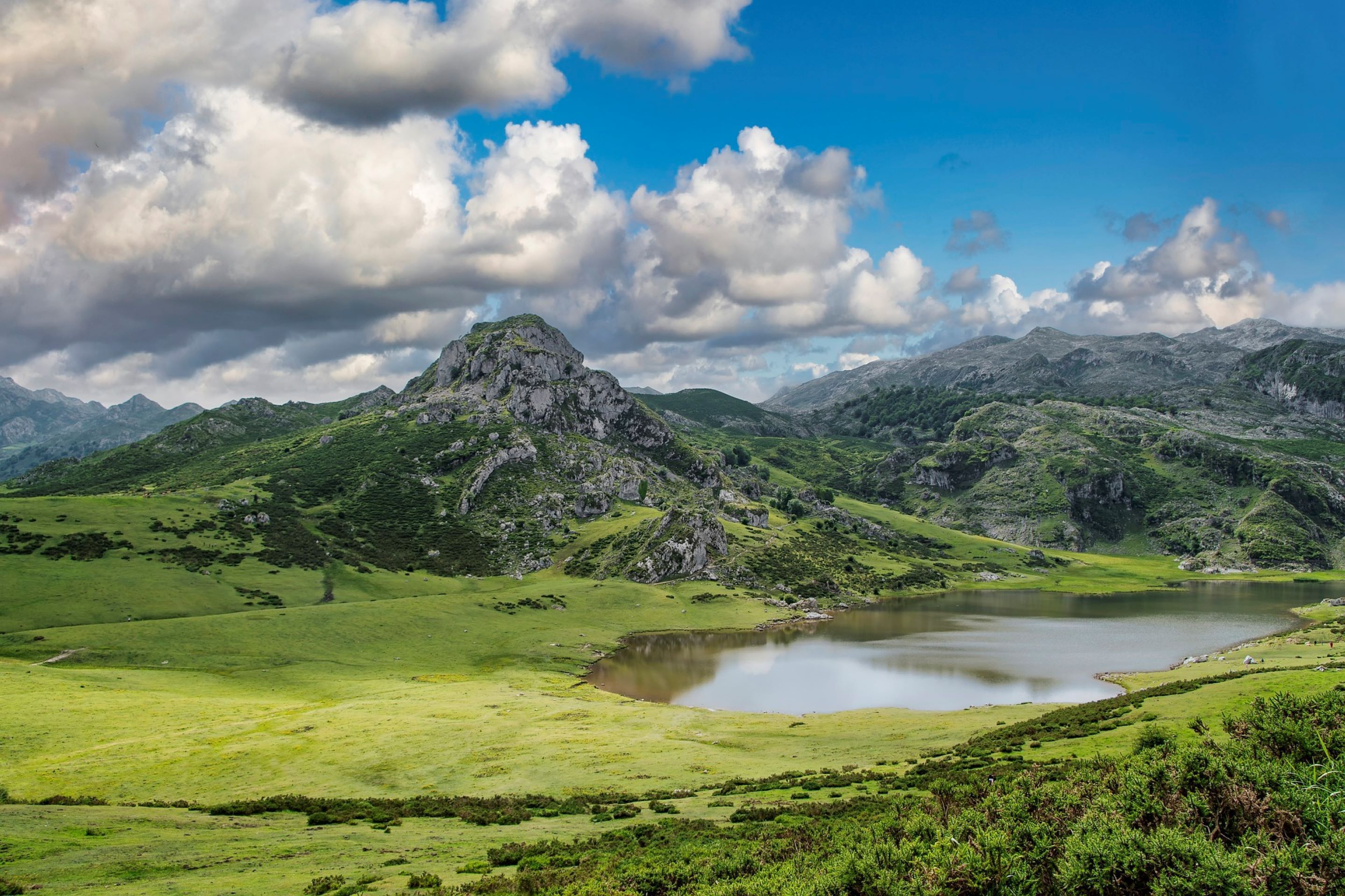 A mountainous landscape with a lake and a prominent rocky peak.