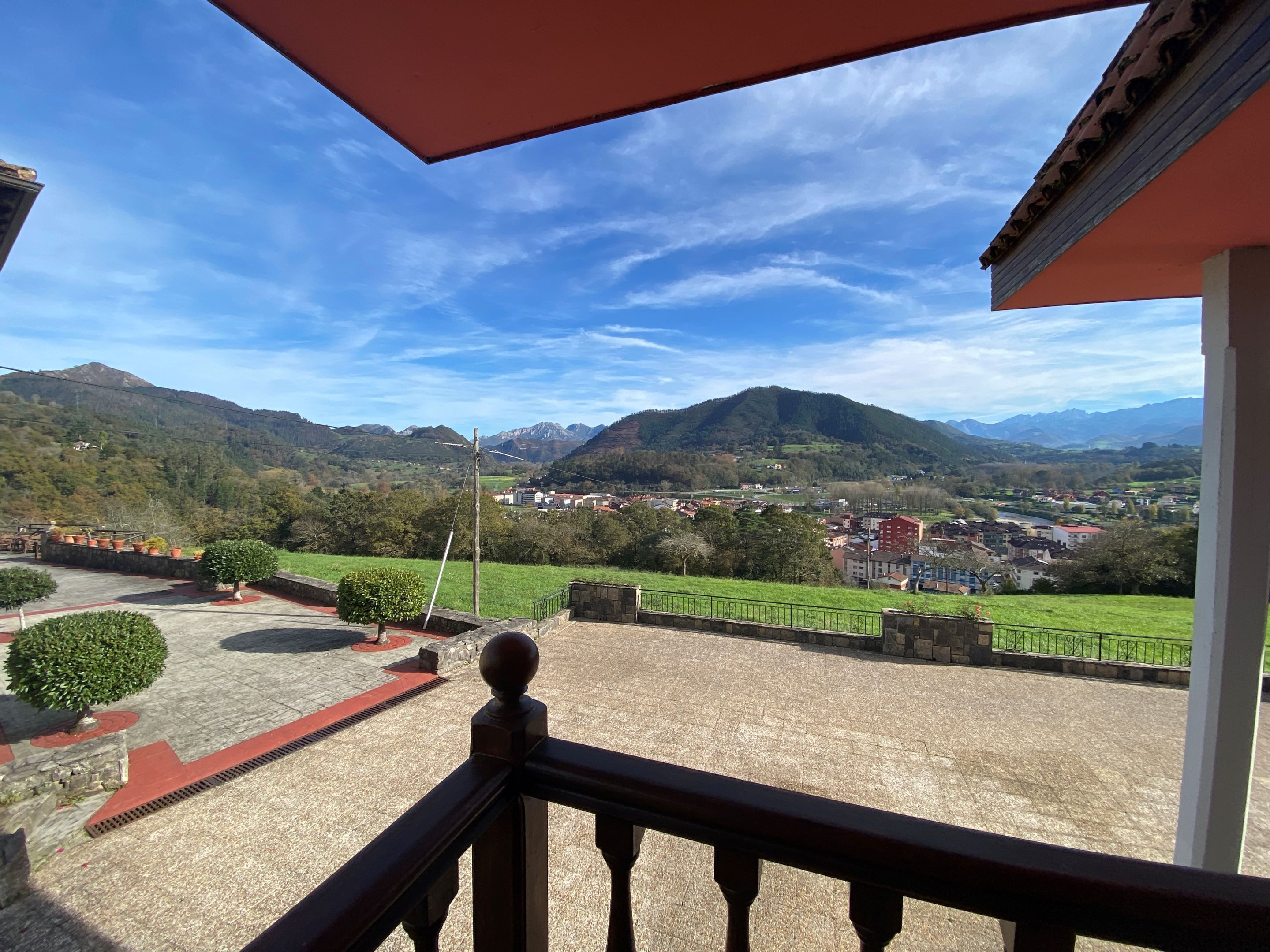 A balcony with a view of a town and mountains.