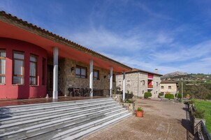 Un edificio con fachada roja, pilares de piedra y techo de piedra.