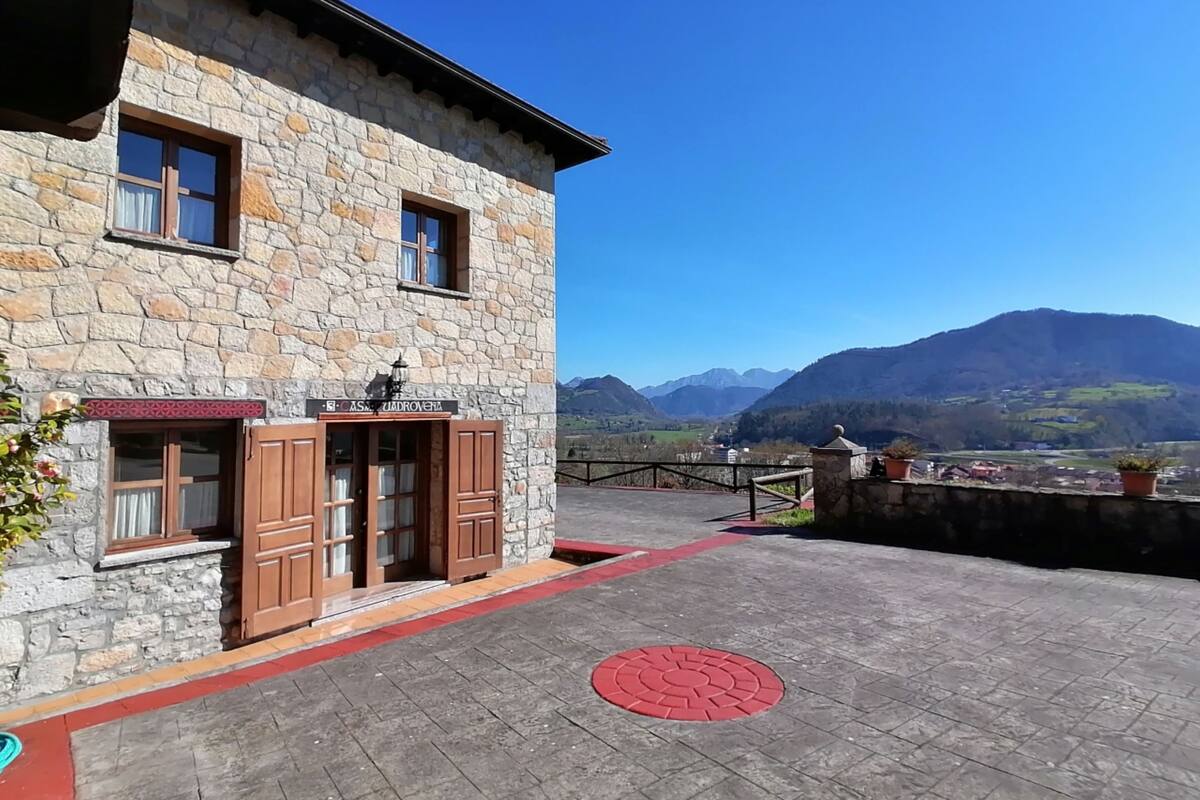 Un bâtiment en pierre avec une enseigne indiquant « CASA RUDOVENIA » et une vue sur les montagnes en arrière-plan.