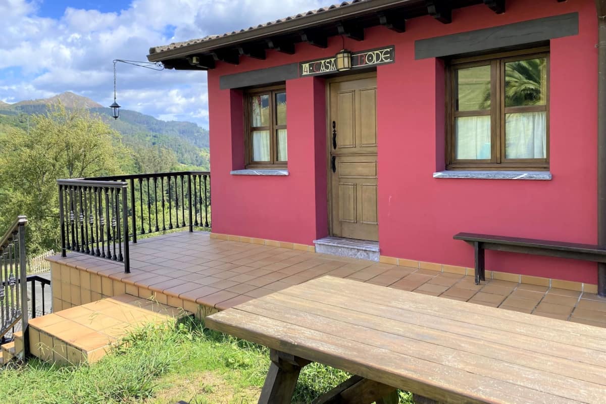 Un bâtiment rouge avec une terrasse en bois et un banc.
