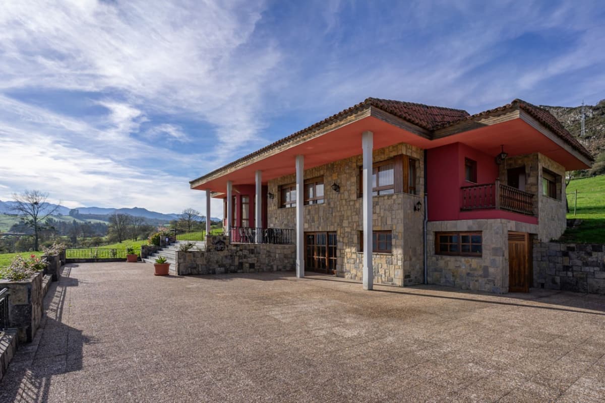 Une maison en pierre à deux étages, avec un toit rouge et une véranda couverte.
