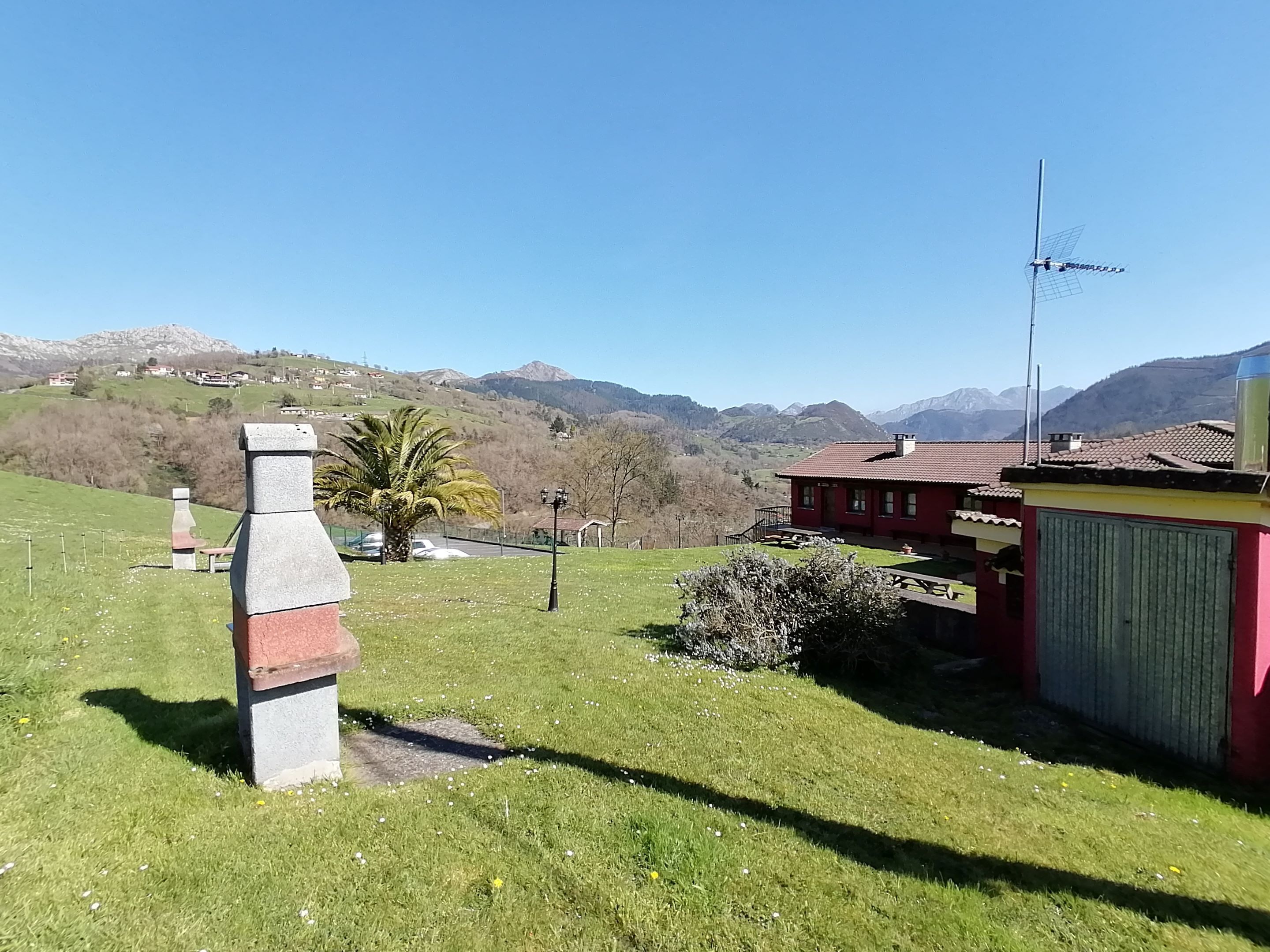 Ländliche Landschaft mit einer Steinstruktur, einem roten Haus und blauem Himmel.