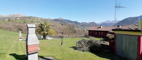 Ländliche Landschaft mit einer Steinstruktur, einem roten Haus und blauem Himmel.