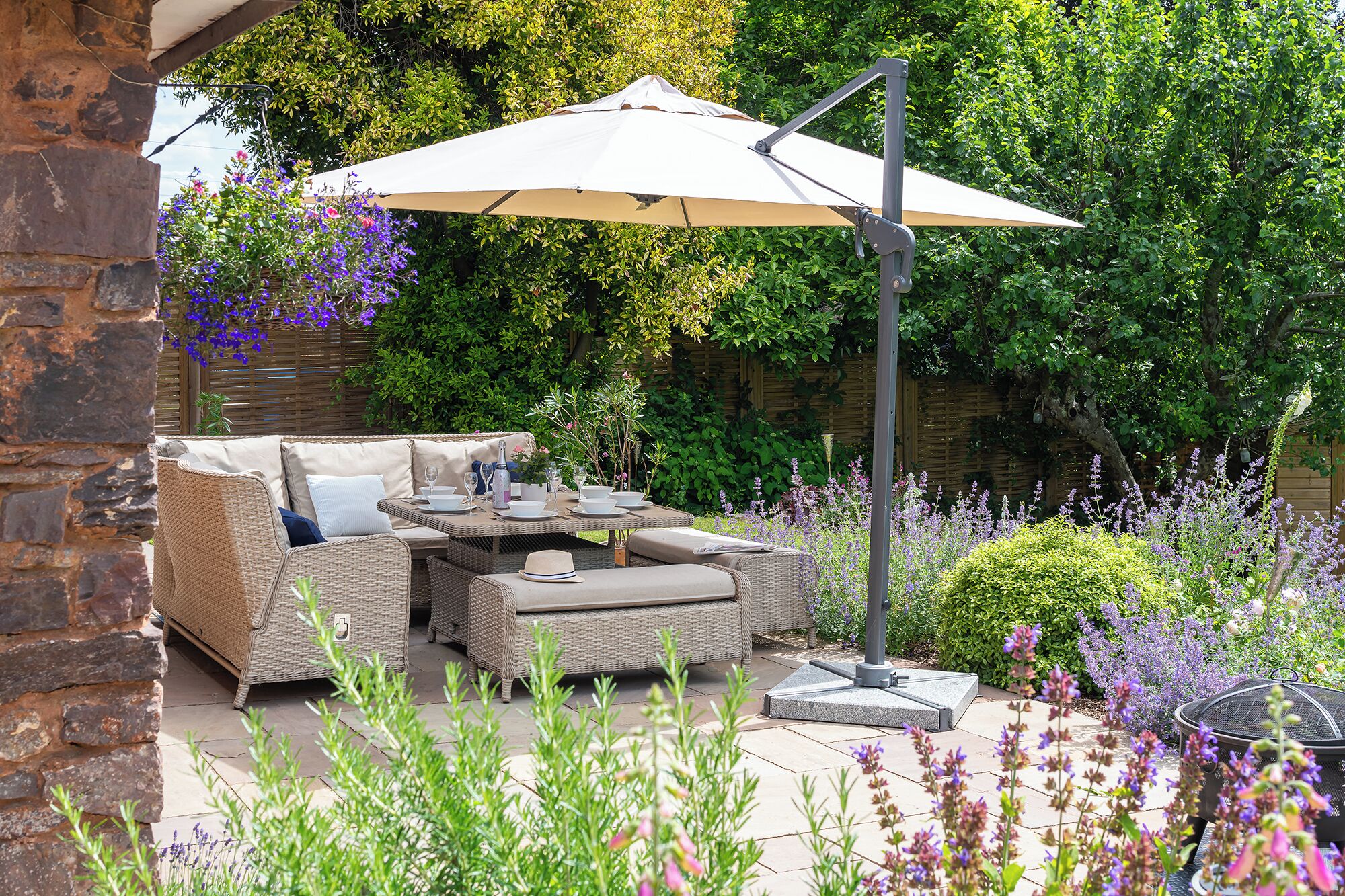An outdoor seating area with wicker furniture, a table, and a large umbrella.