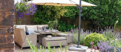 An outdoor seating area with wicker furniture, a table, and a large umbrella.