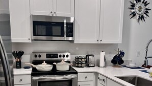 Une cuisine moderne avec des meubles blancs, des appareils en acier inoxydable et un tapis bleu qui apporte une touche de couleur.