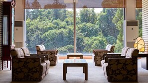 A room with a large window, a sofa set, a coffee table, and a lamp. - Misasa Royal Hotel (Misasa)