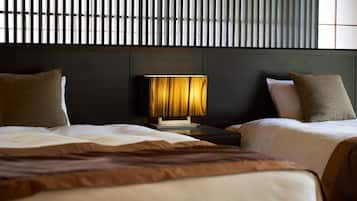 A hotel room with two beds, a nightstand with a lamp, and a dark headboard.