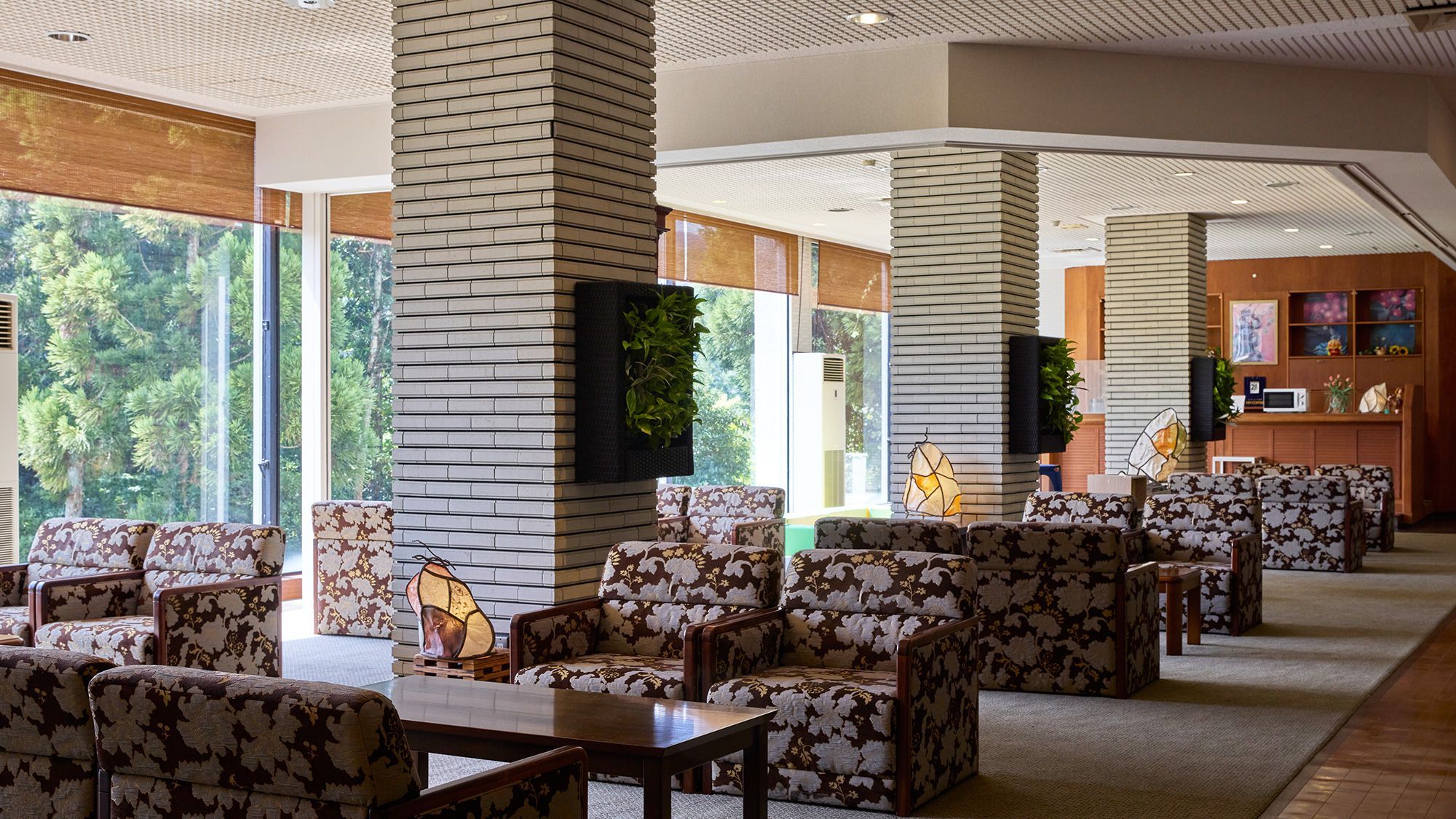 A hotel lobby with seating arrangements, large windows, and a reception area.