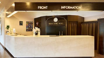 A reception desk with a clock and a sign for 'MISASA ROYAL HOTEL' above it.