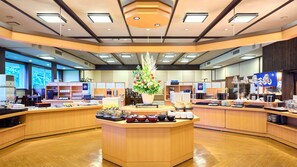 A hotel lobby with a central reception desk, a large floral arrangement, and a buffet area with various food items. - Misasa Royal Hotel (Misasa)