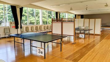 A room with ping pong tables, numbered signs, and chairs.
