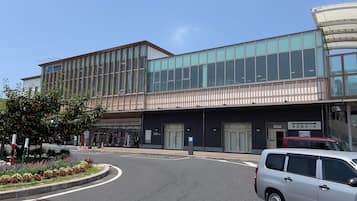 A modern building with a glass facade, a covered entrance, and a parking area with a white car.
