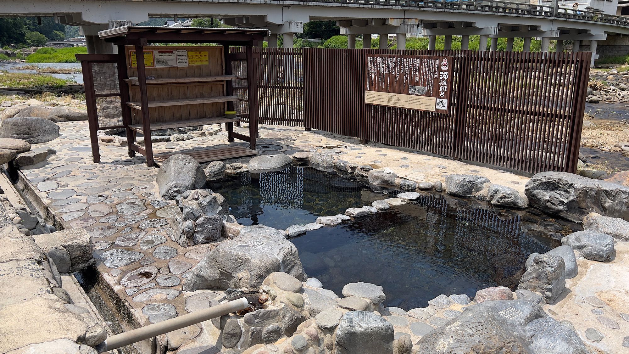 Un onsen japonés tradicional con estructura de madera y zona de baño de piedra.