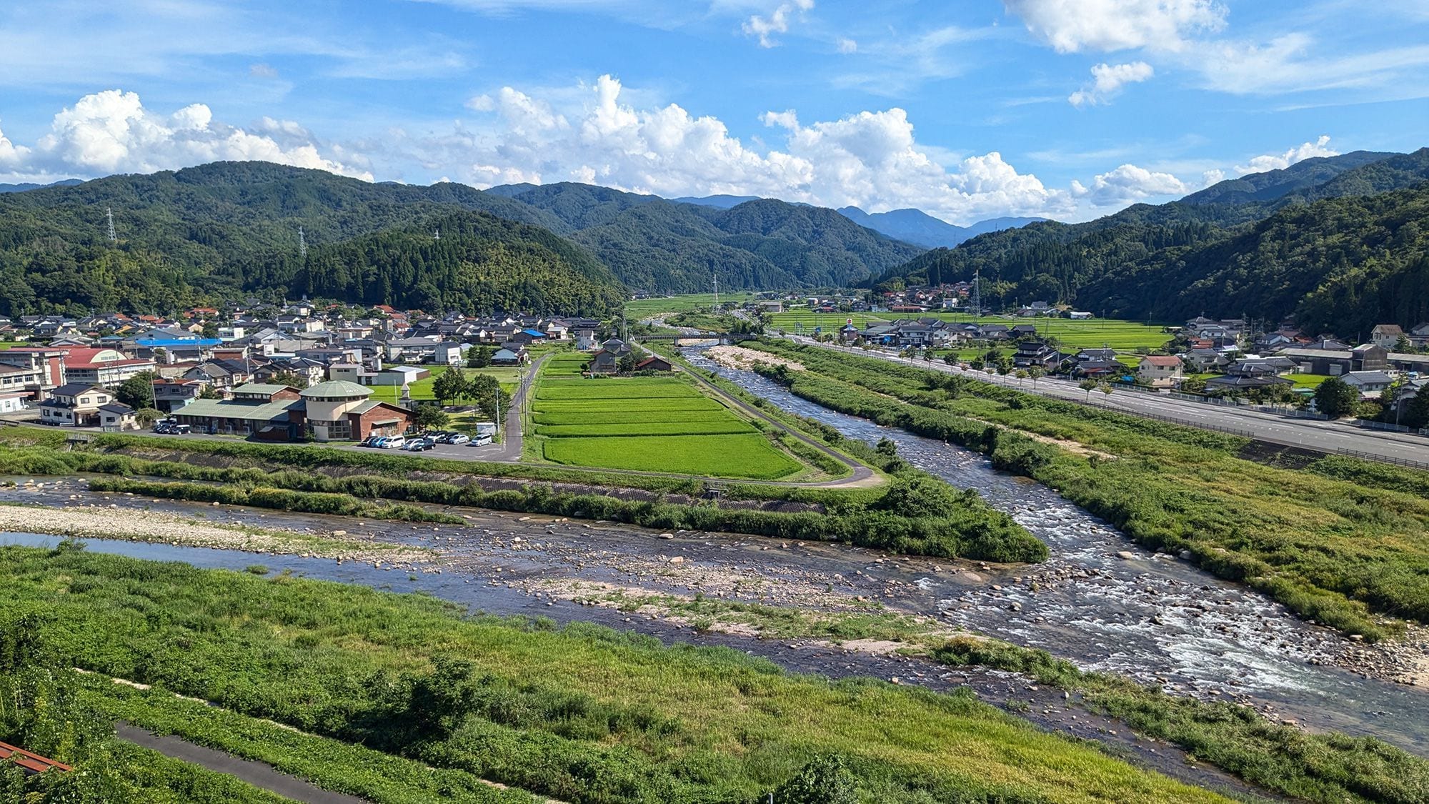 A river flowing through a town with houses and fields on both sides.