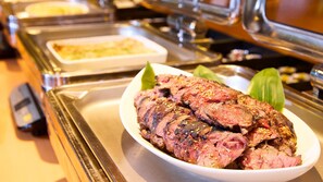 Un bufé con una variedad de platos, incluyendo un plato de carne en rodajas adornado con semillas de sésamo.