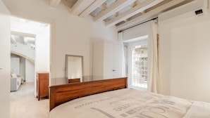 A bedroom with a wooden bed, a wardrobe, a mirror, and a view of the outside through a window. - Il Cortile sul Vicolo Alla Giudecca by Wonderful Italy (Syracuse)