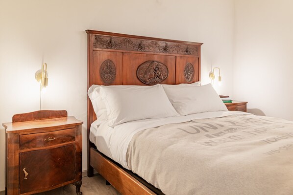 A neatly made bed with a wooden headboard, two bedside tables, and wall-mounted lamps. - Il Cortile sul Vicolo Alla Giudecca by Wonderful Italy (Syracuse)