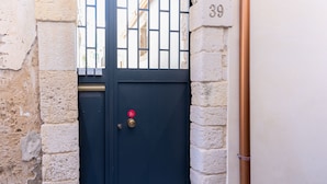 A dark blue door with a brass handle and a red emergency exit sign, set in a stone wall with the number 39 visible. - Il Cortile sul Vicolo Alla Giudecca by Wonderful Italy (Syracuse)