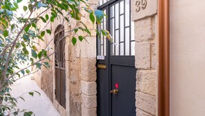 A narrow alleyway with a stone building, a metal gate, and a number '39' on the wall. - Il Cortile sul Vicolo Alla Giudecca by Wonderful Italy (Syracuse)