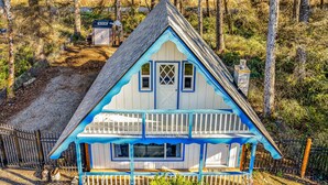 A two-story house with a blue and white exterior, a front porch, and a fenced yard. - Captain Green s Cabin (Copalis Beach)