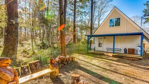 A cabin with a wooden deck, surrounded by trees and a fenced area with wooden posts. - Captain Green s Cabin (Copalis Beach)