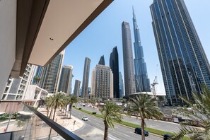 A cityscape with modern high-rise buildings, palm trees, and a clear sky. - Exclusive 2BR Downtown Apt w Burj Khalifa Views (Dubai)