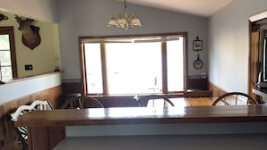 A kitchen with wooden cabinets, a large window, and a chandelier. - Rustic 2-bedroom cabin on Boyd Pond (Russell)