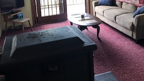 A living room with a television, a sofa, a coffee table, and a fireplace. - Rustic 2-bedroom cabin on Boyd Pond (Russell)