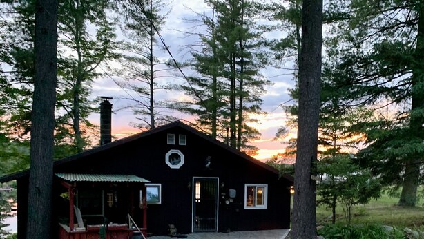 A cabin with a porch, a chimney, and a door. - Rustic 2-bedroom cabin on Boyd Pond (Russell)