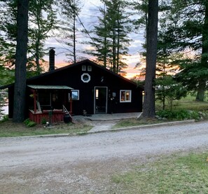 A cabin with a porch, a chimney, and a door.
