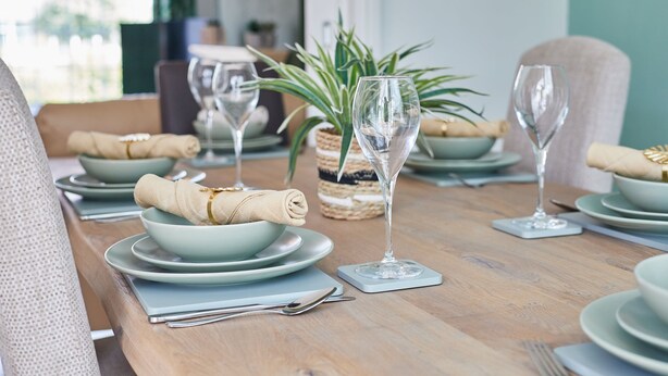A dining table set with plates, bowls, and wine glasses, with a plant and a basket in the background. - Chester home only 2km from famous Races and Roman City, sleeps 6 by Restfully (Chester)