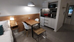 A compact hotel room with a bed, bedside table, lamp, and a small kitchenette with a microwave and toaster. - Estudio en Palermo III (Buenos Aires)