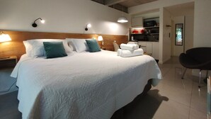 A hotel room with a large bed, bedside lamps, a small kitchenette, and a chair. - Estudio en Palermo III (Buenos Aires)