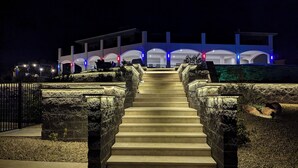 Un escalier menant à un bâtiment doté de nombreuses arcades et d’une entrée fermée par un portail.