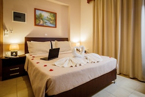 A hotel room with a bed, a nightstand, a lamp, a painting on the wall, and a window with curtains.