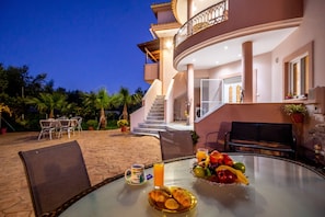 A dining area with a table set for breakfast, including croissants, fruit, and orange juice.