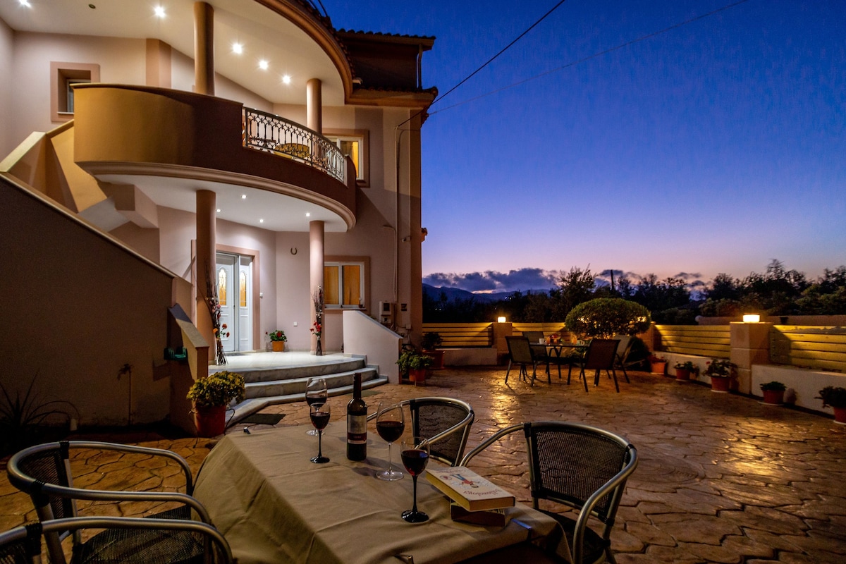 A spacious outdoor patio with a dining table set for two, surrounded by chairs.