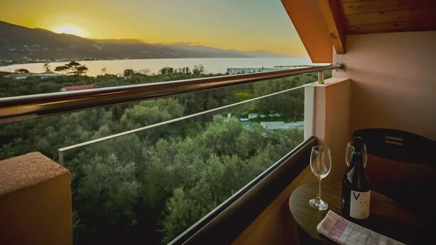 Ein Balkon mit Blick auf einen See und Berge bei Sonnenuntergang.