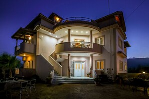 A two-story house with a balcony, a staircase, and outdoor seating.