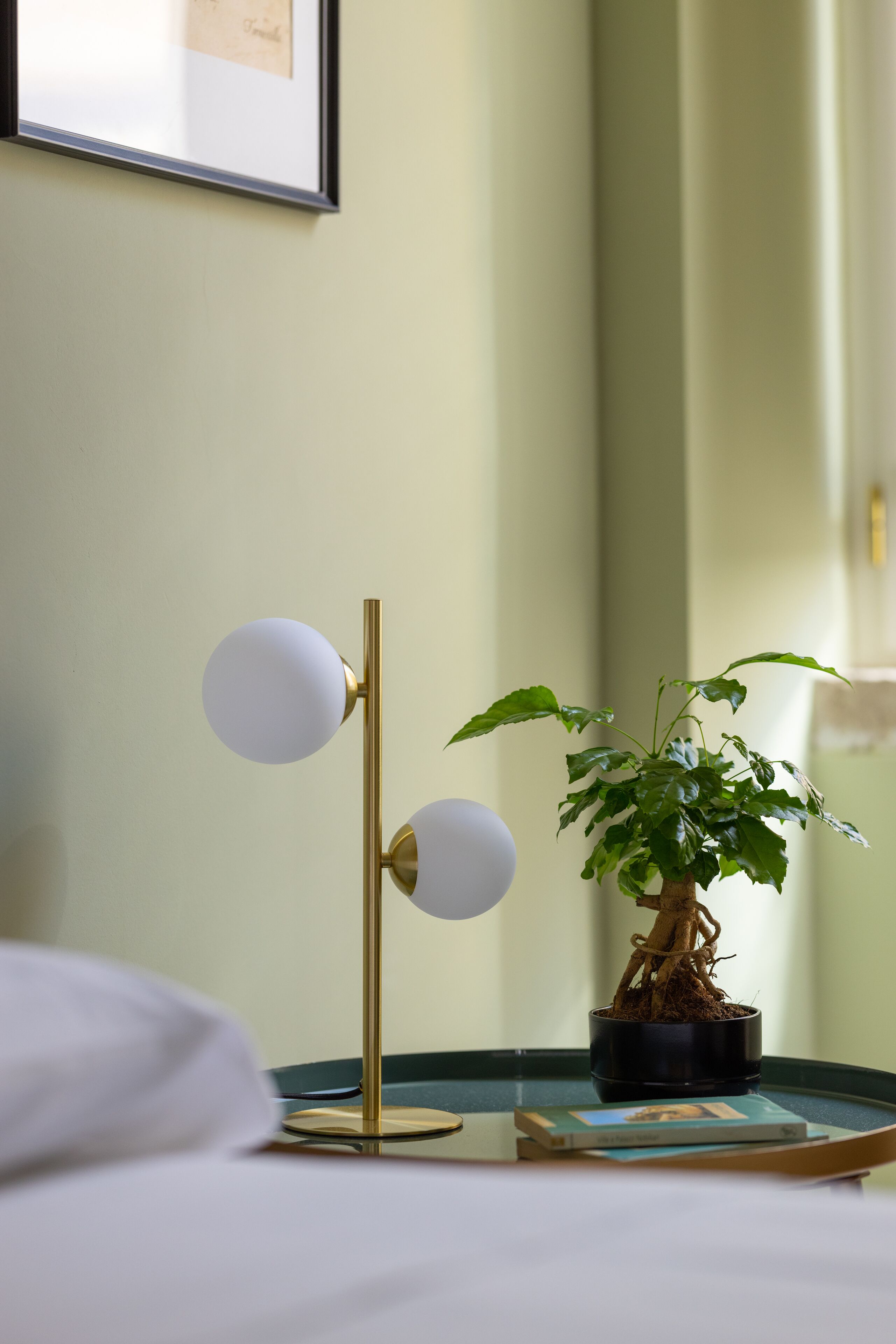 A bedside table with a potted plant and a lamp.