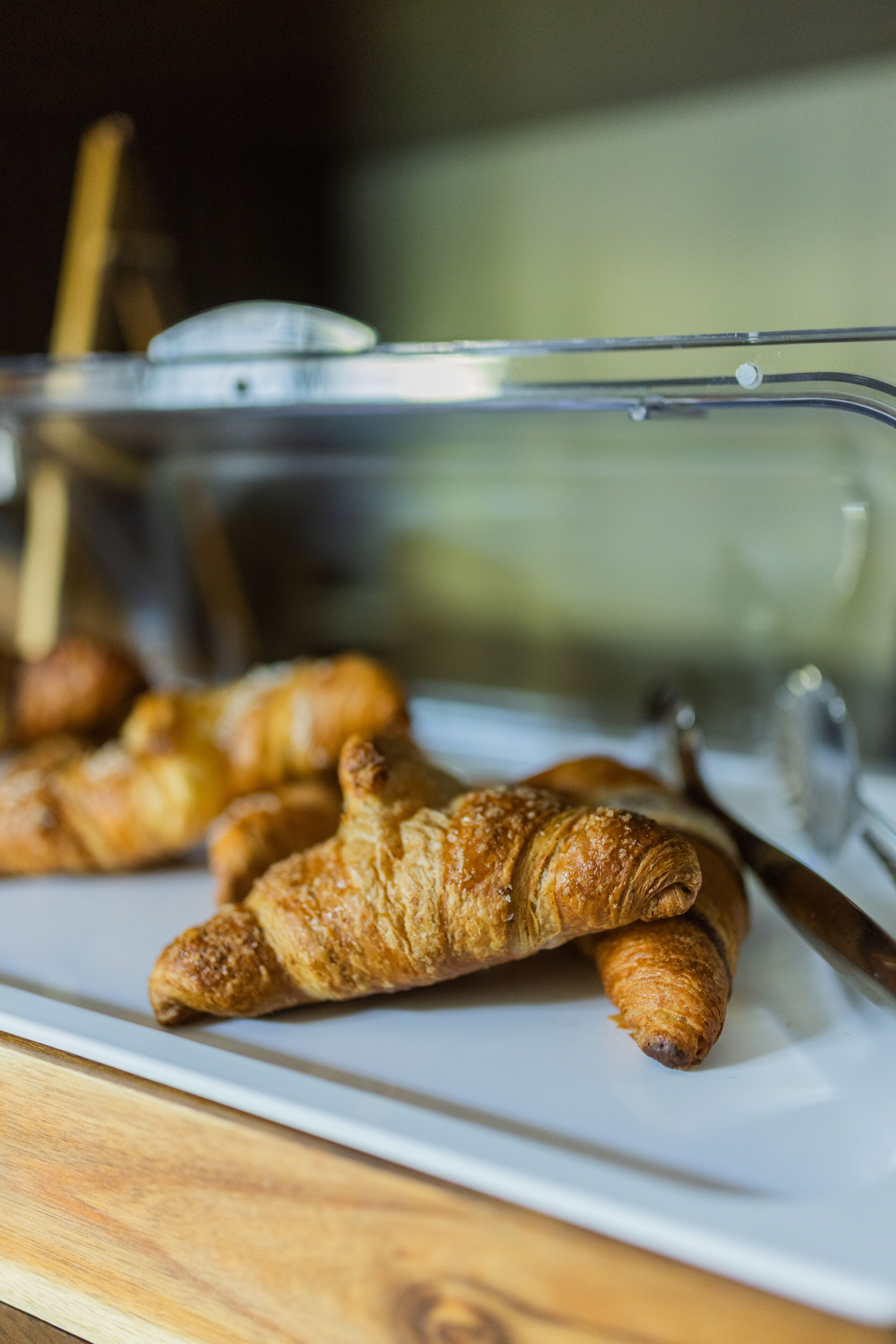 A white plate with several croissants on a wooden table.
