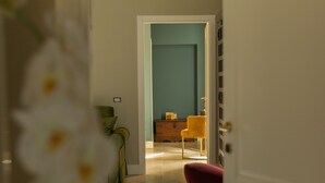 Een hal met een deur naar een kamer, met een blauwe wand en een houten dressoir.